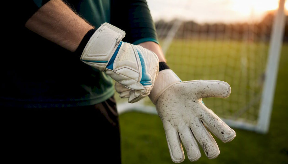 Der Torwart streift sich auf dem Spielfeld die Handschuhe über.